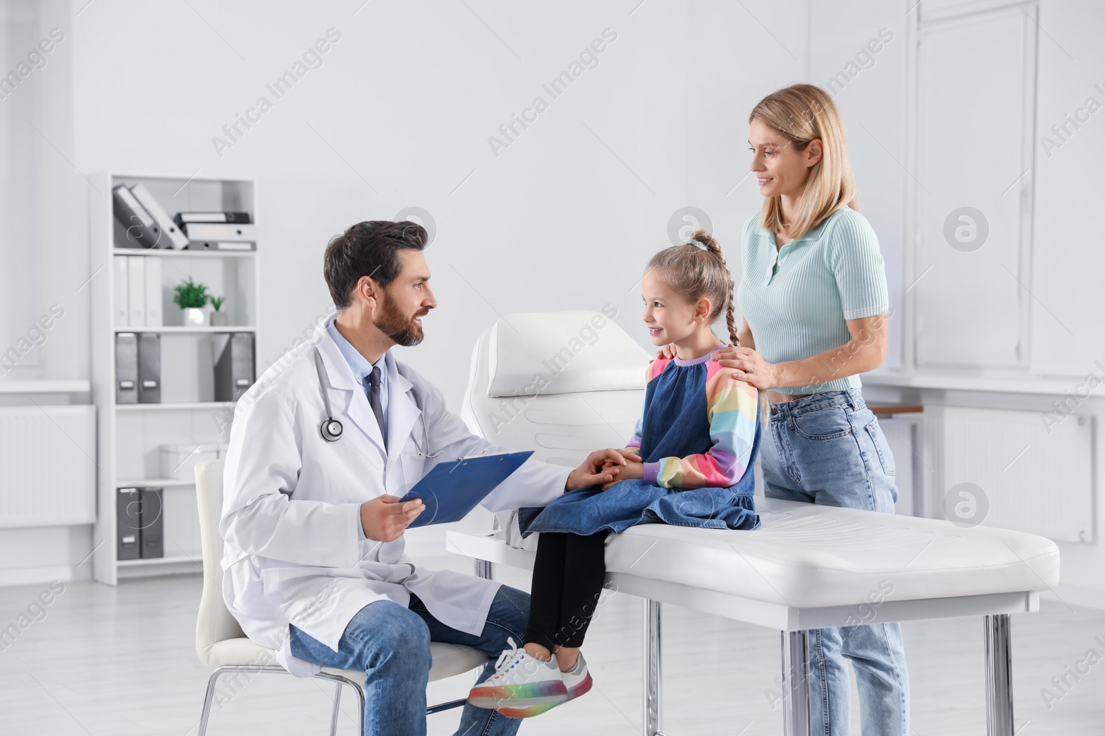 Photo of Mother and daughter having appointment with doctor. Pediatrician consulting patient in clinic