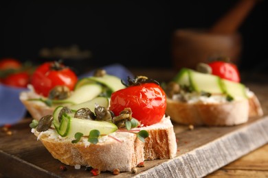 Bruschettas with capers, vegetables and cream cheese served on wooden board, closeup