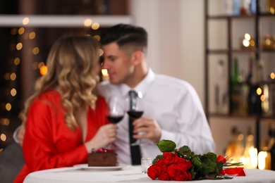 Photo of Lovely couple celebrating Valentine's day in restaurant, focus on table with red roses