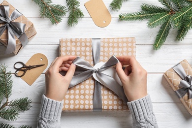 Woman wrapping Christmas gift at wooden table, top view