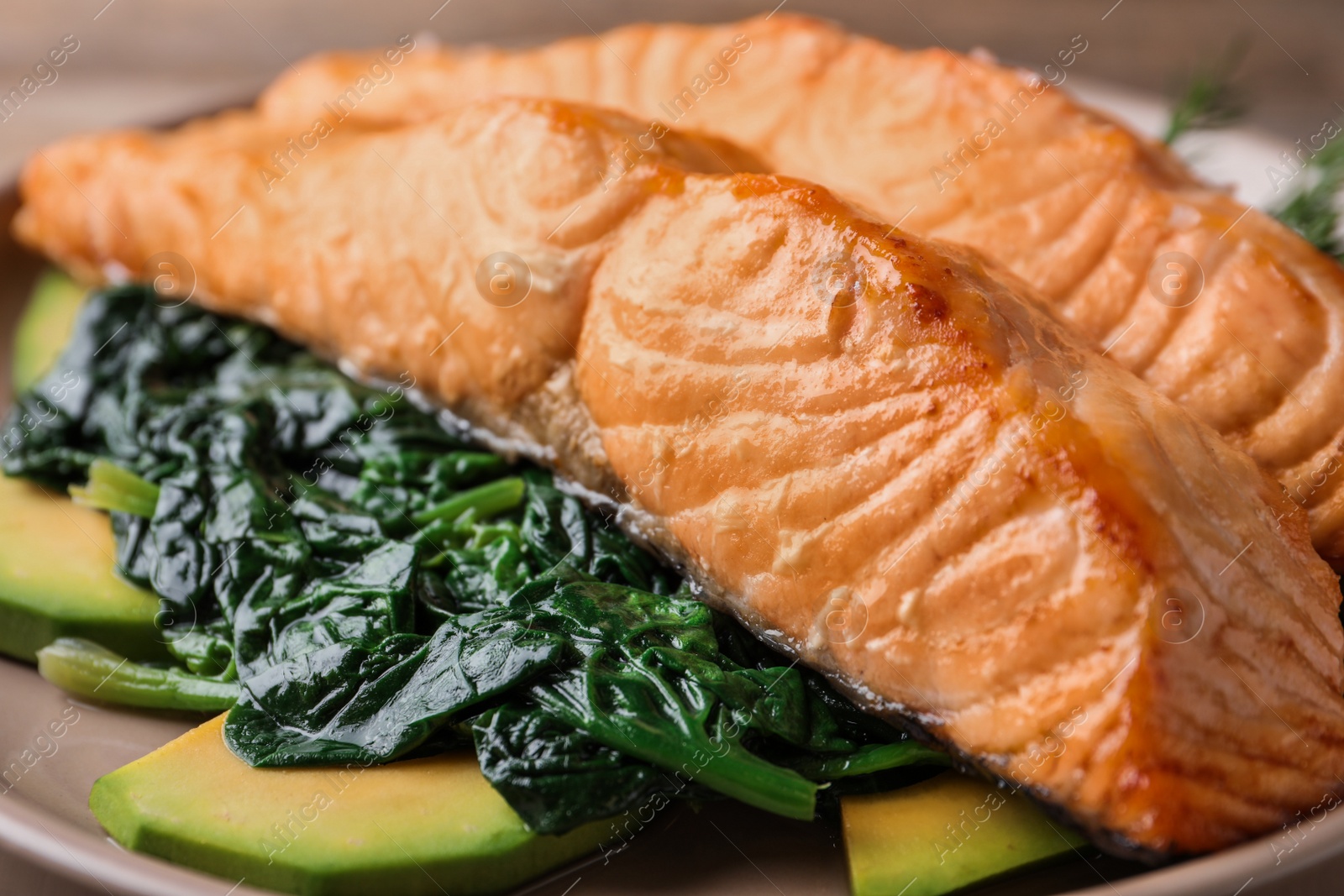 Photo of Tasty salmon with spinach and avocado on plate, closeup