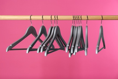 Wooden rack with clothes hangers on color background