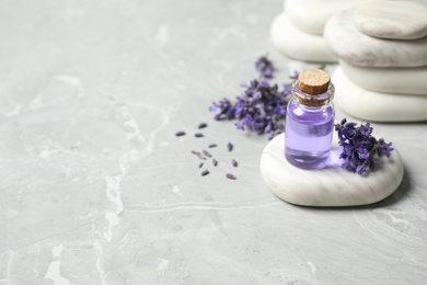 Photo of Stones, bottle of essential oil and lavender flowers on marble table. Space for text