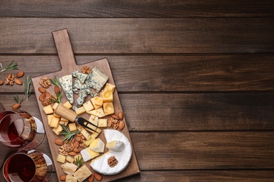 Photo of Cheese plate with rosemary and nuts on wooden table, flat lay. Space for text