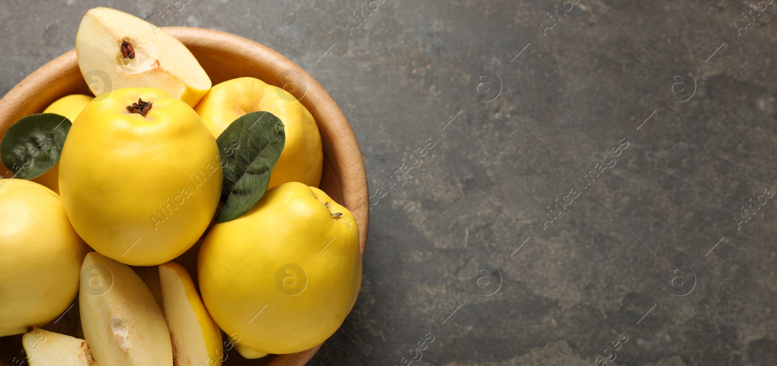 Image of Fresh ripe organic quinces with leaves on grey table, top view with space for text. Banner design