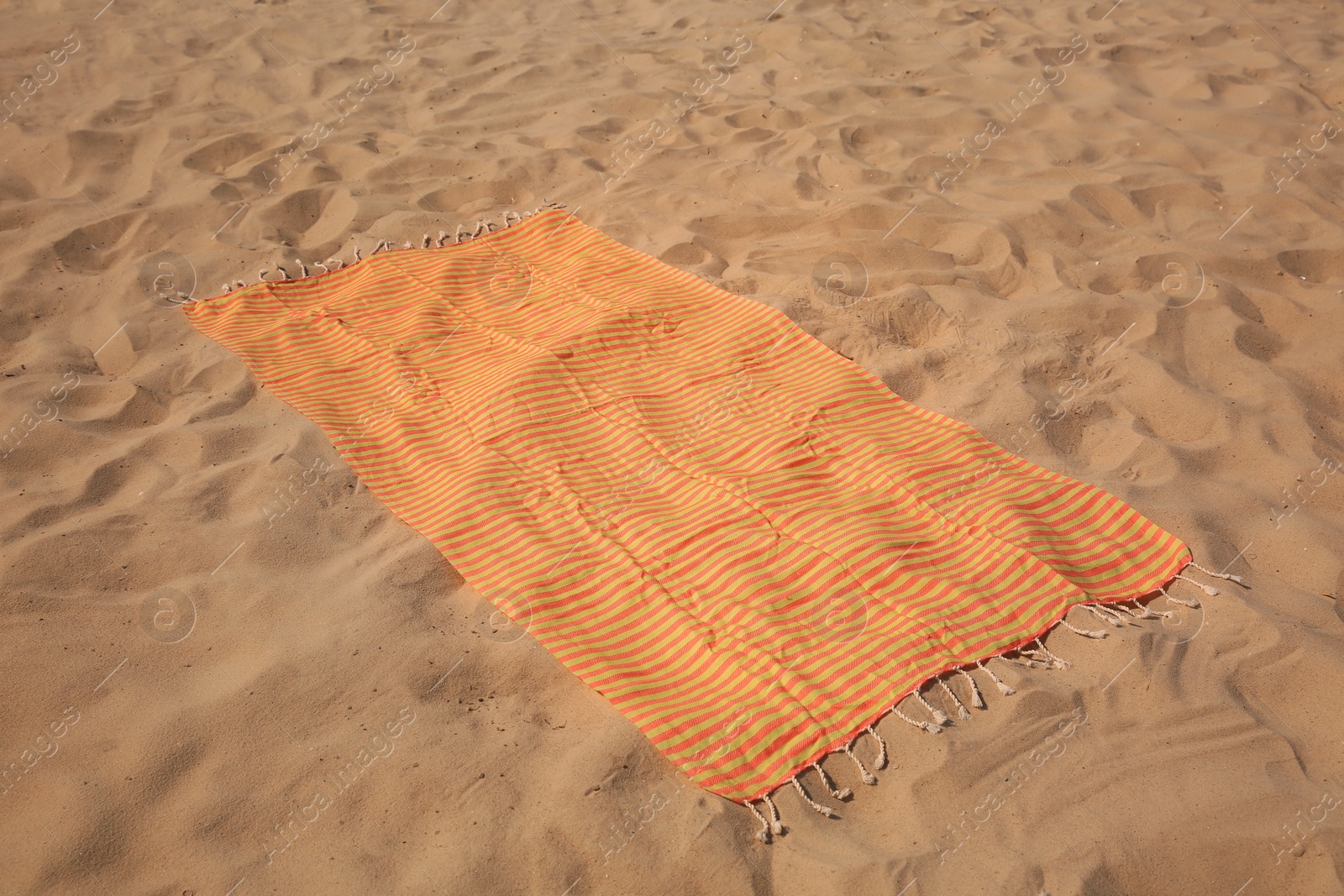 Photo of Beautiful orange striped beach towel on sand