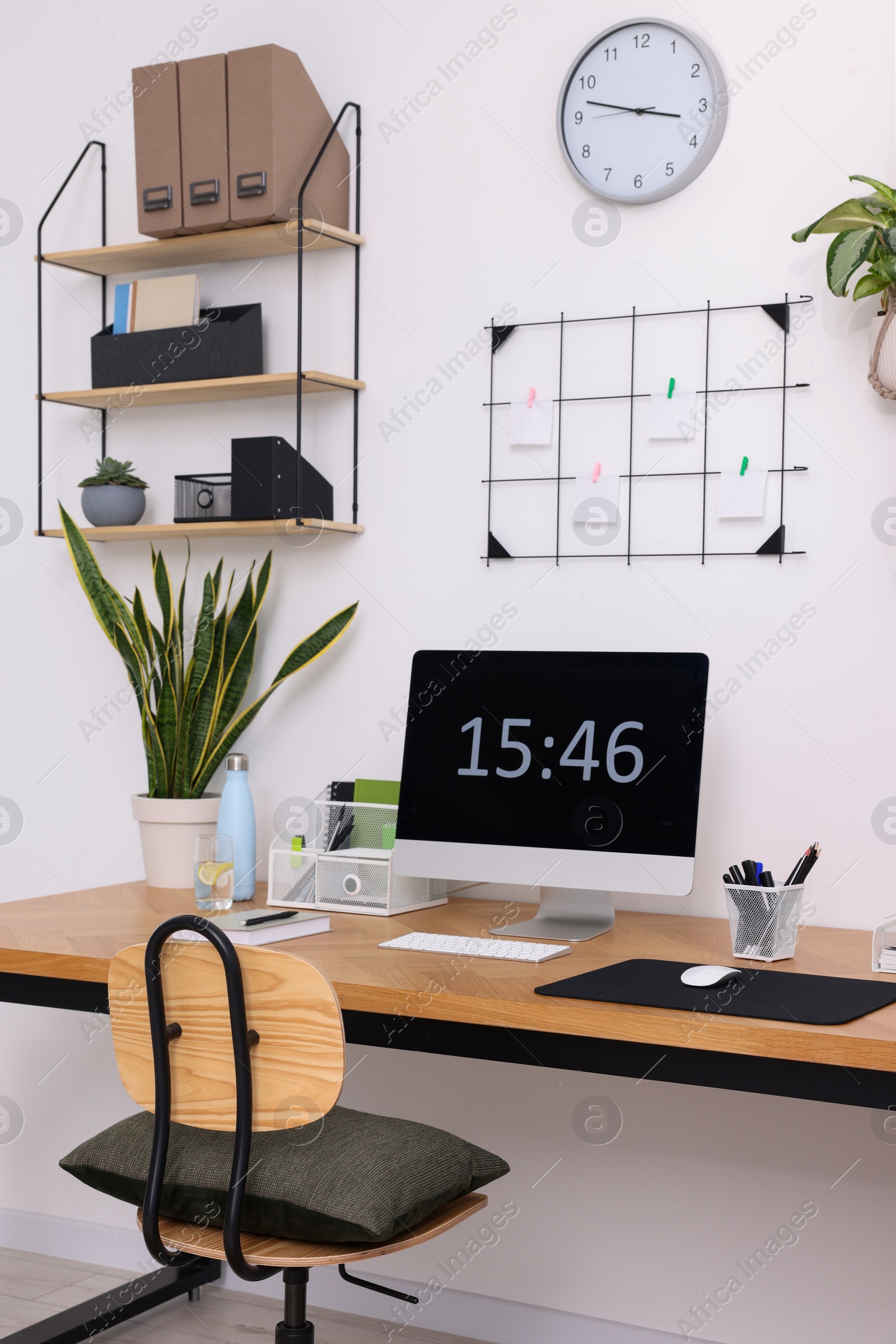 Photo of Cozy workplace with computer, modern furniture and houseplants at home