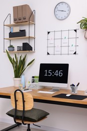 Cozy workplace with computer, modern furniture and houseplants at home