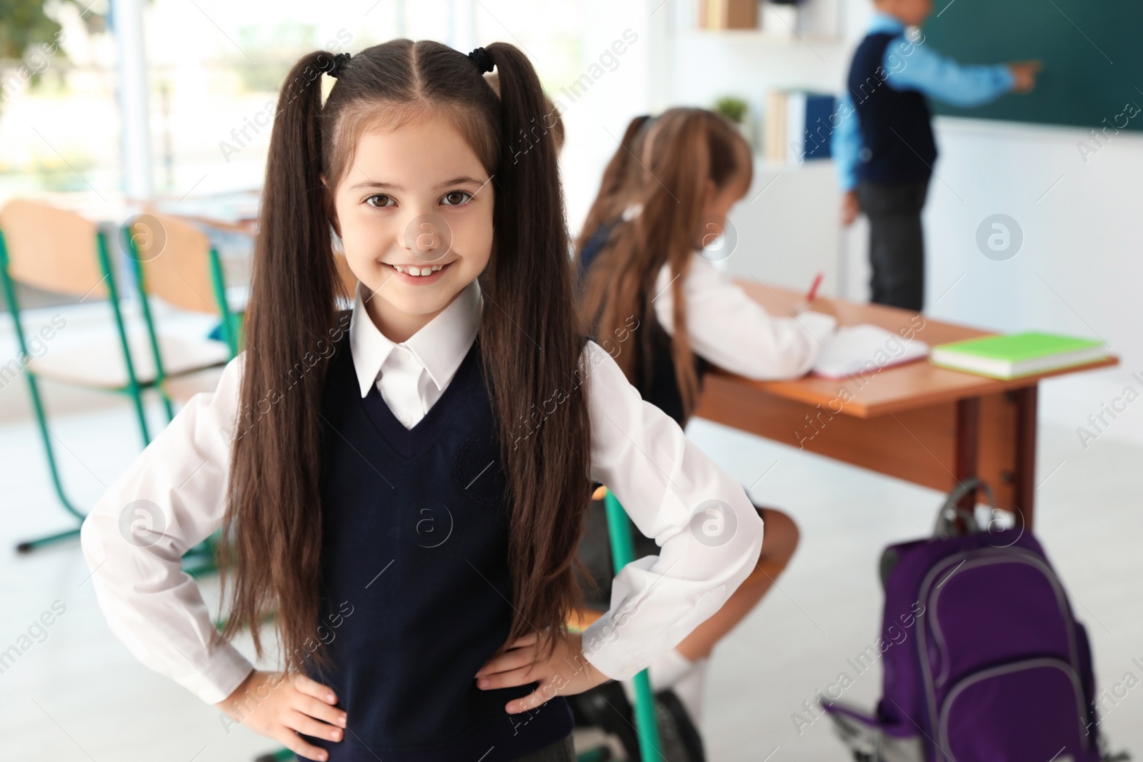 Photo of Little girl in classroom. Stylish school uniform