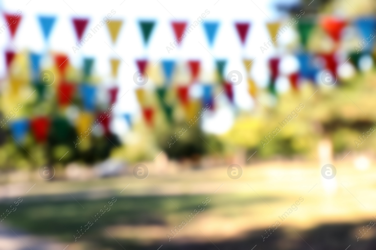 Photo of Blurred view of colorful bunting flags in park. Party decor