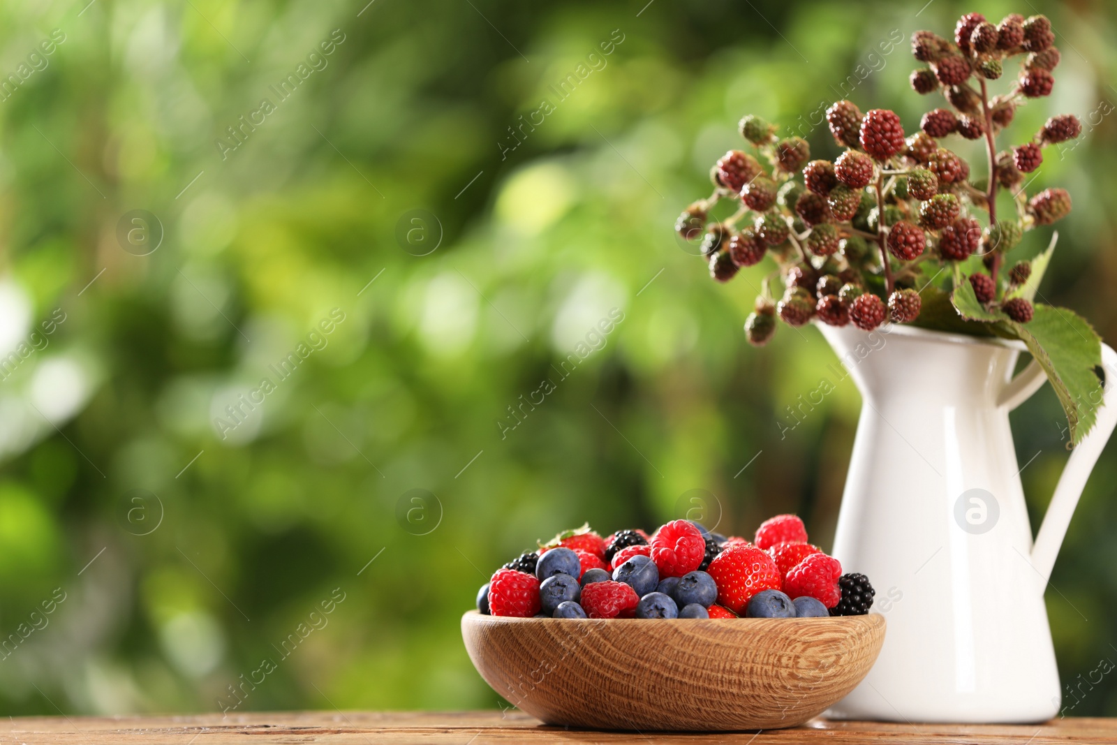 Photo of Different fresh berries on wooden table outdoors, space for text