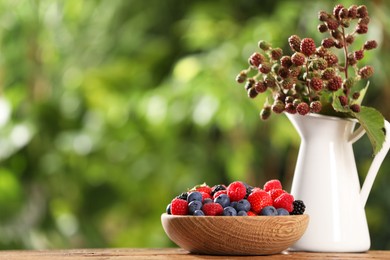 Different fresh berries on wooden table outdoors, space for text