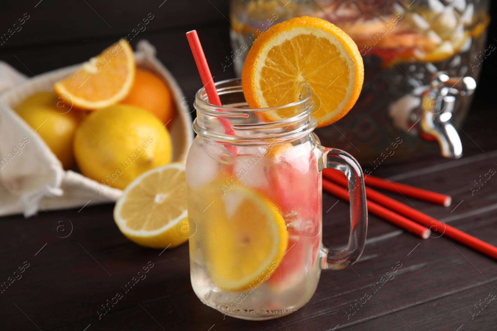 Photo of Delicious refreshing lemonade with orange slices in mason jar on wooden table