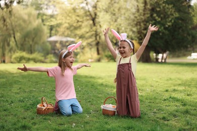 Photo of Easter celebration. Cute little girls in bunny ears with wicker baskets outdoors