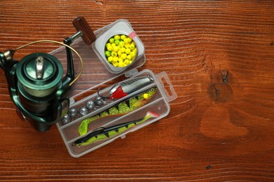 Photo of Fishing tackle. Spinning reel, lures and bait on wooden table, flat lay. Space for text
