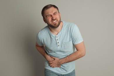 Man suffering from acute appendicitis on light grey background