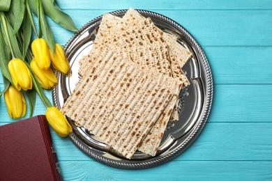 Photo of Flat lay composition of matzo, Torah and flowers on wooden background. Passover (Pesach) Seder