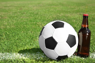 Photo of Soccer ball with beverage on green football field grass. Space for text
