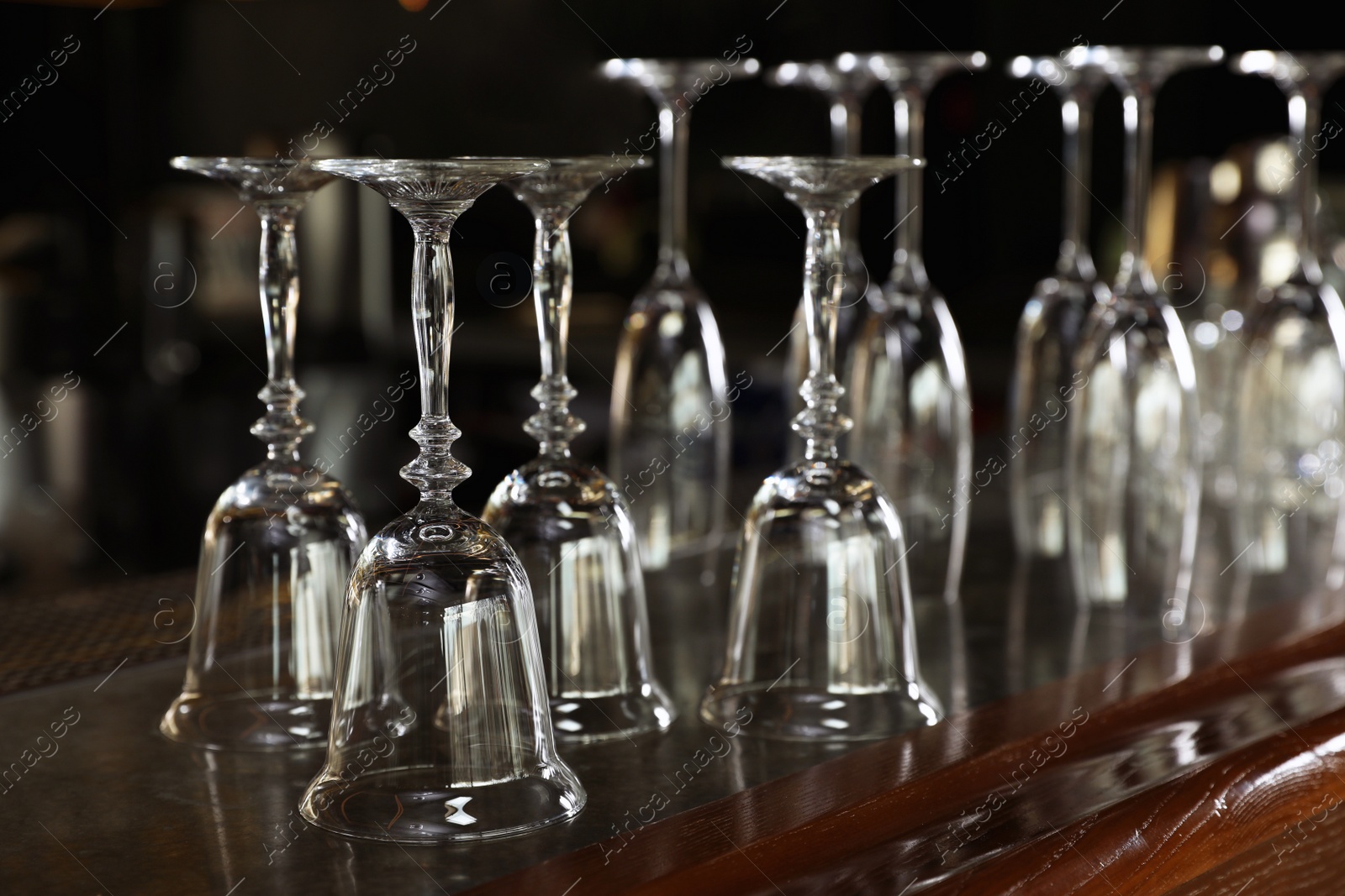 Photo of Different empty clean glasses on counter in bar