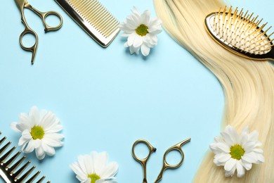 Photo of Flat lay composition with professional hairdresser tools, flowers and blonde hair strand on light blue background