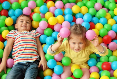 Photo of Cute little children playing in ball pit at indoor amusement park