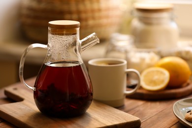 Photo of Teapot with delicious tea on wooden table, space for text