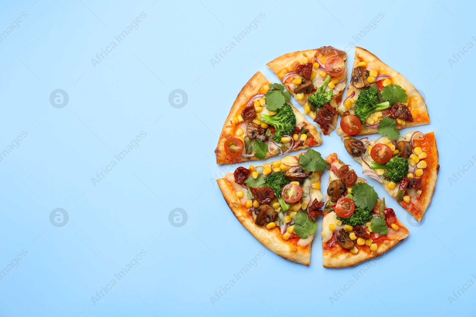 Photo of Delicious vegetarian pizza with mushrooms, vegetables and parsley on light blue background, top view. Space for text