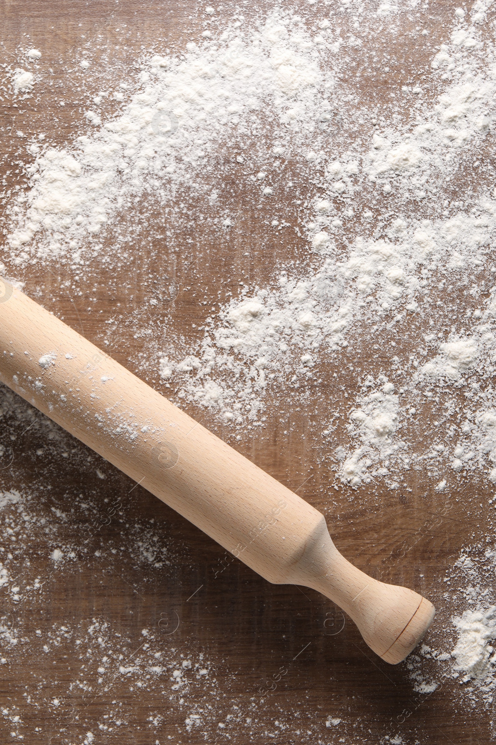 Photo of Scattered flour and rolling pin on wooden table, top view