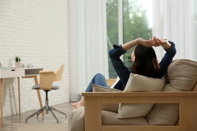 Photo of Teenage girl relaxing on sofa at home, back view. Space for text