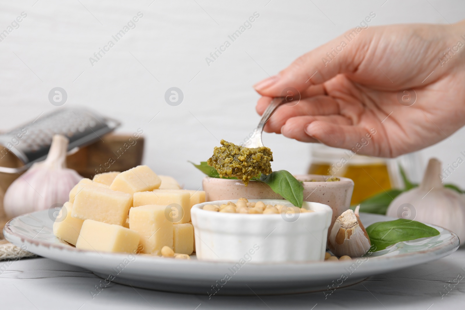 Photo of Woman eating delicious pesto sauce at white table, closeup