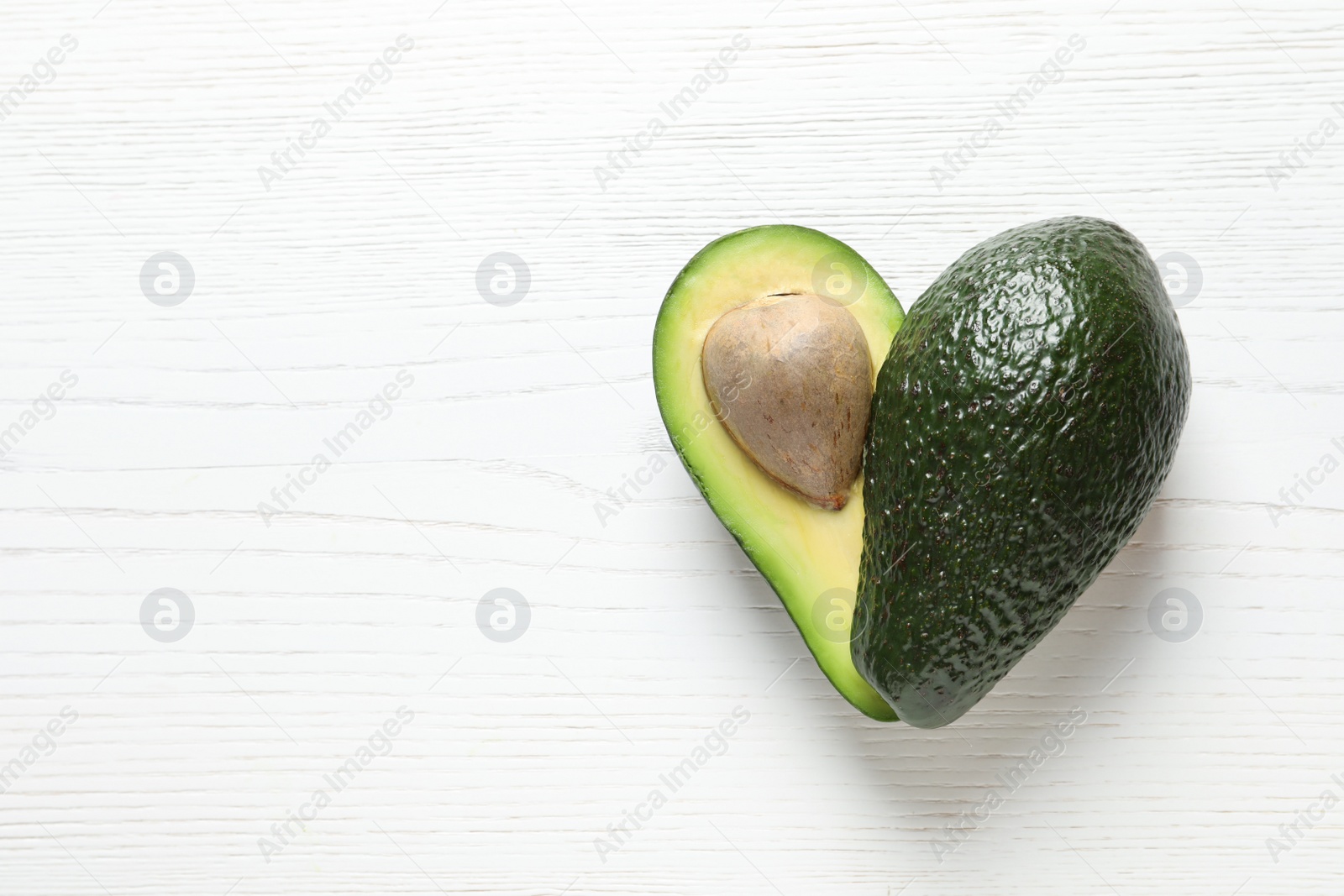 Photo of Fresh avocado on wooden background, top view with space for text. Heart-healthy diet