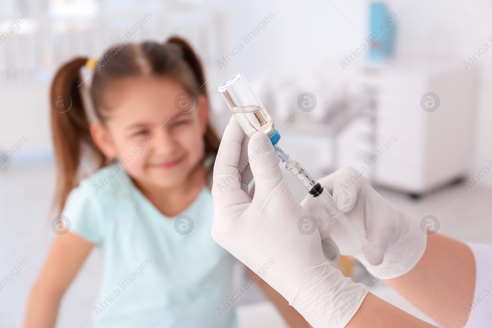 Photo of Doctor filling syringe with medicine and child on background. Vaccination day