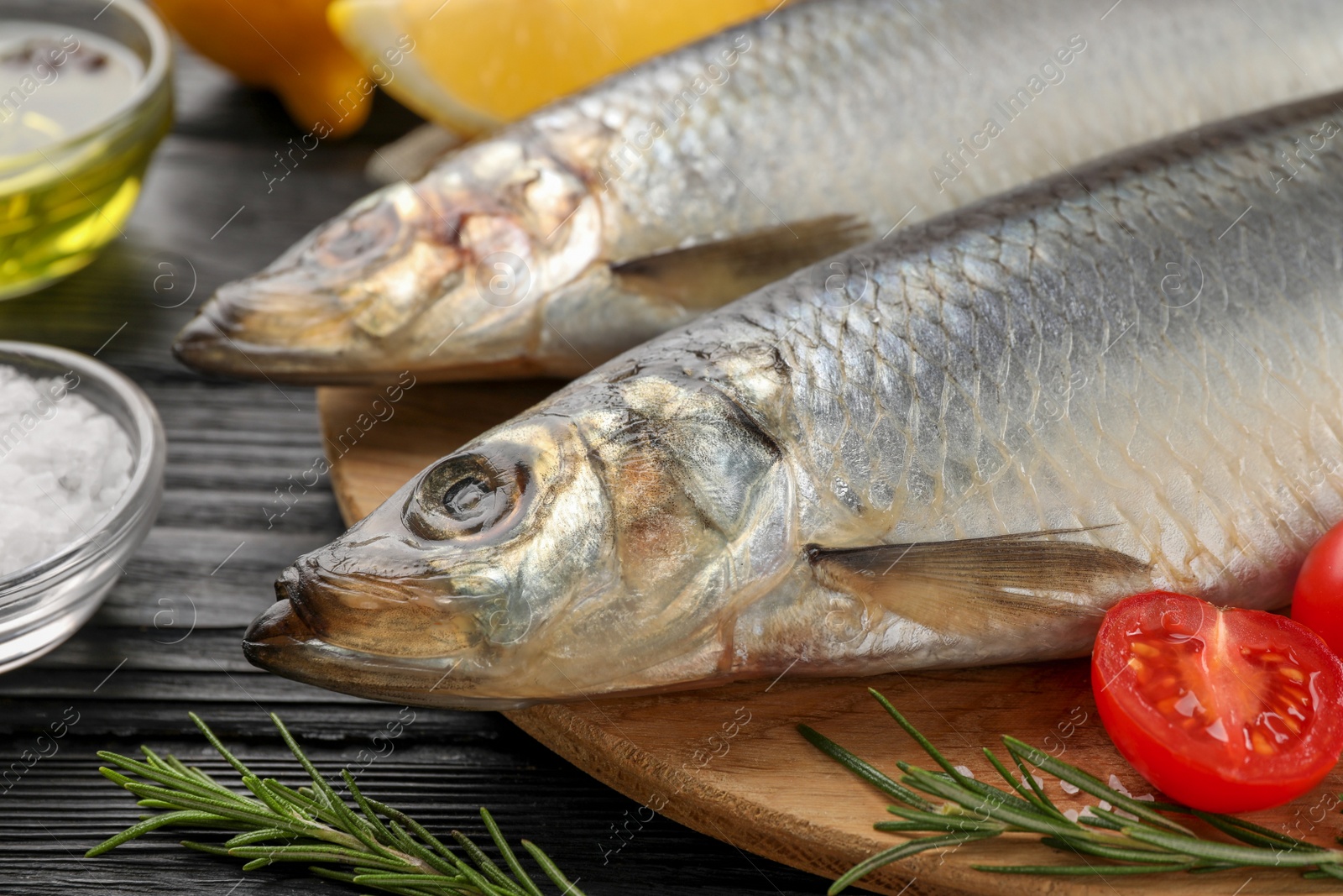 Photo of Delicious salted herrings and ingredients on black wooden table, closeup