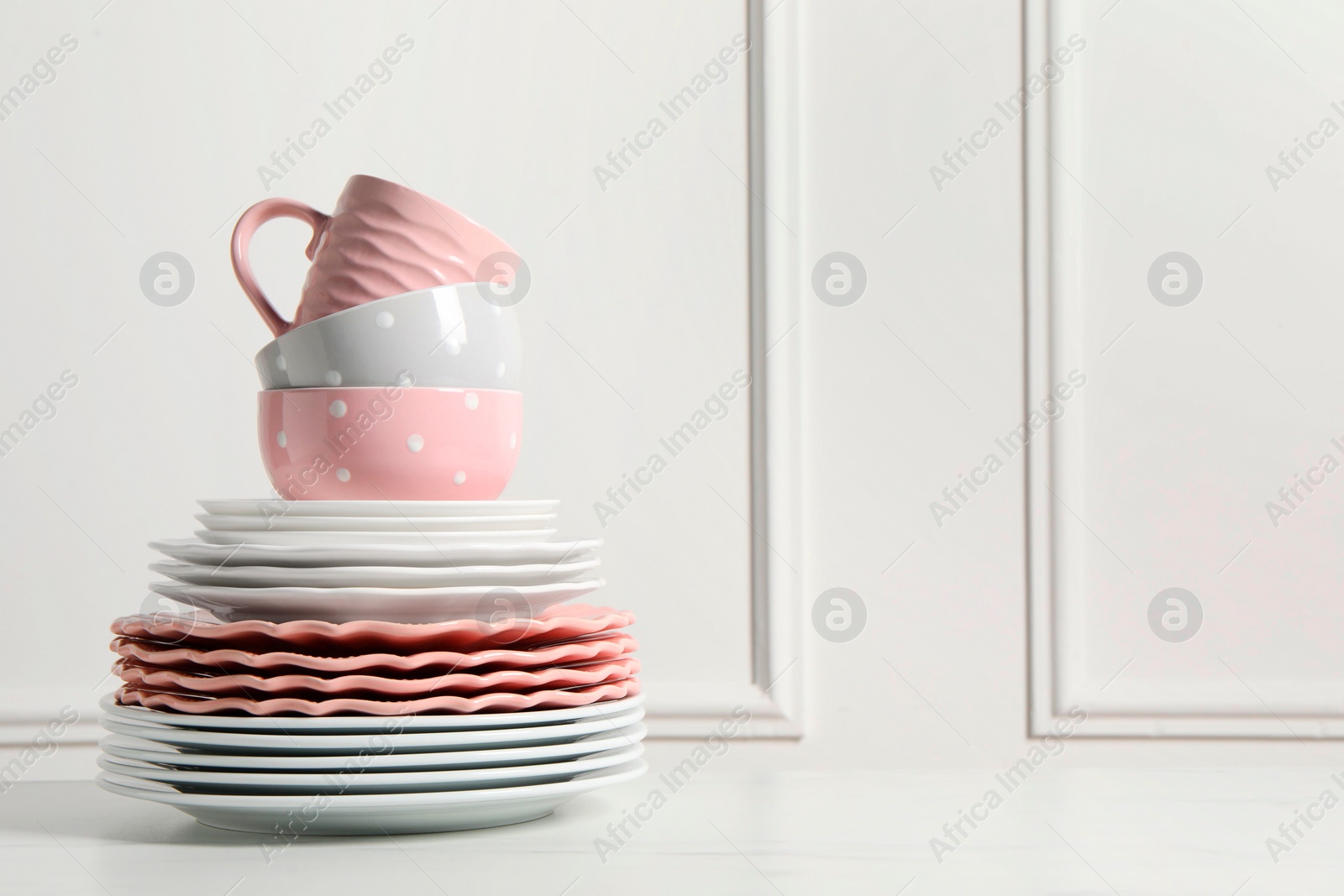 Photo of Beautiful ceramic dishware and cup on white marble table, space for text