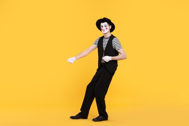 Photo of Funny mime artist in hat posing on orange background