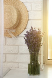 Beautiful lavender bouquet and straw hat near window indoors