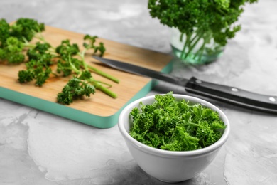 Photo of Fresh curly parsley in bowl on grey table