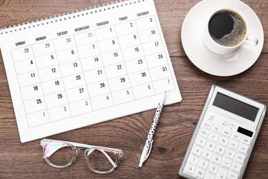 Photo of Flat lay composition with calendar and cup of coffee on wooden table