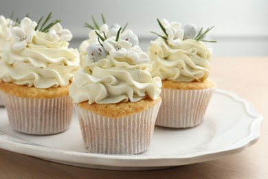 Photo of Tasty Easter cupcakes with vanilla cream on wooden table, closeup