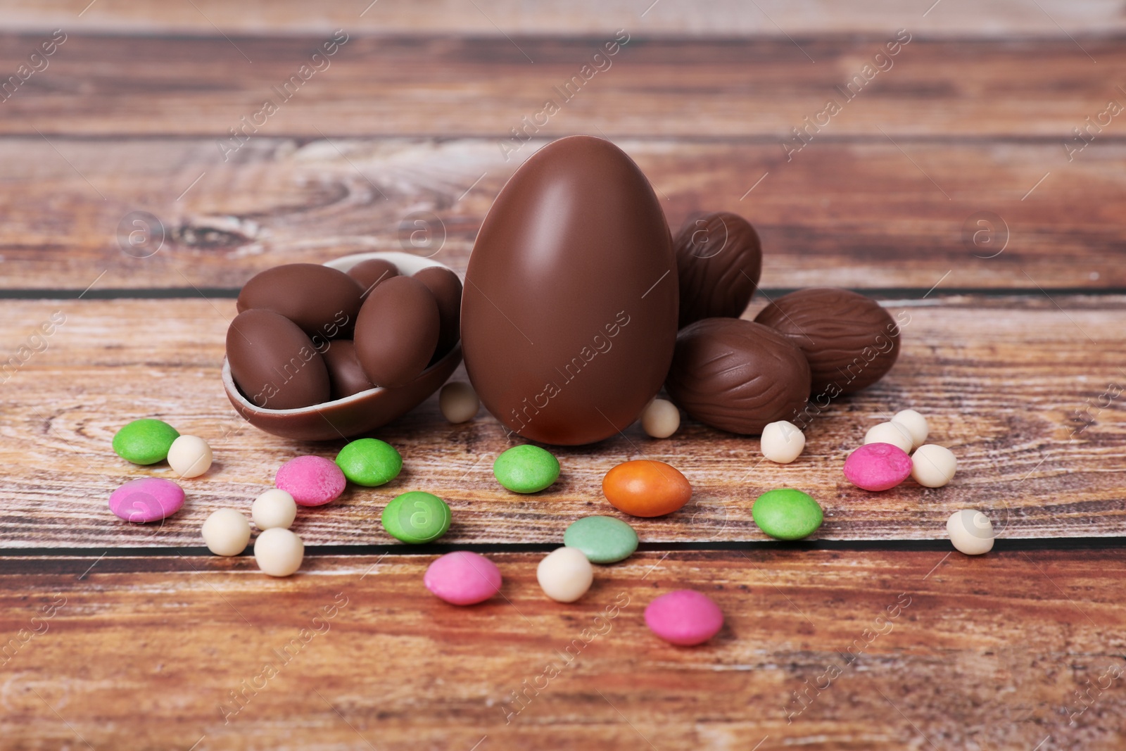 Photo of Delicious chocolate eggs and colorful candies on wooden table