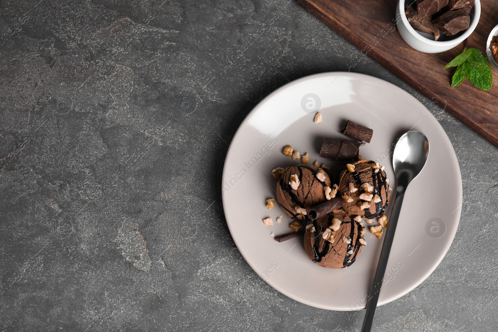 Photo of Flat lay composition with plate of chocolate ice cream on grey table, space for text