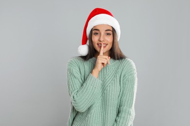 Photo of Happy woman in Santa hat on grey background. Christmas countdown