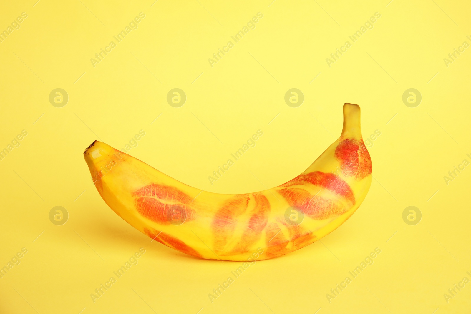 Photo of Fresh banana with red lipstick marks on yellow background. Oral sex concept