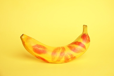 Fresh banana with red lipstick marks on yellow background. Oral sex concept