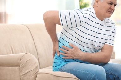 Photo of Mature man suffering from back pain at home