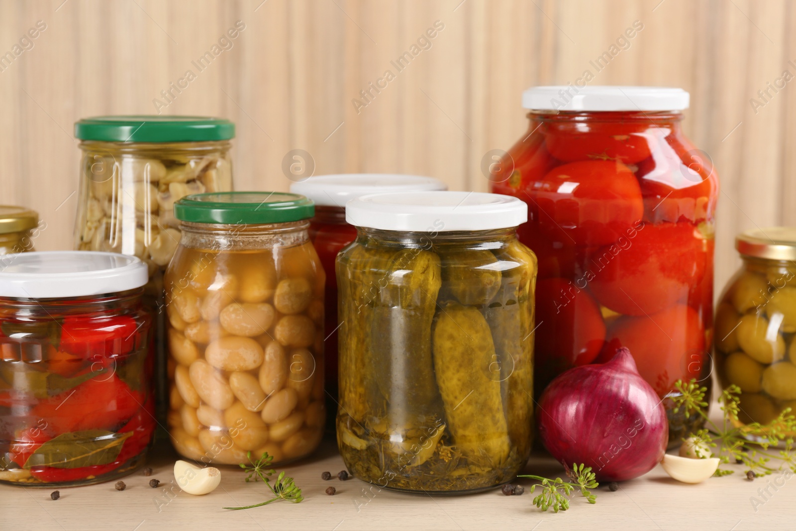 Photo of Jars of pickled vegetables on wooden table