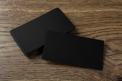 Photo of Blank black business cards on wooden background. Mockup for design