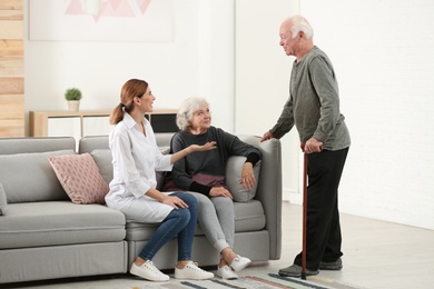 Elderly spouses with female caregiver in living room