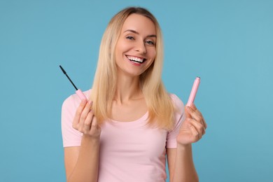 Photo of Beautiful woman with mascara on light blue background