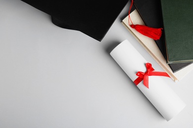 Graduation hat, books and student's diploma white background, top view. Space for text